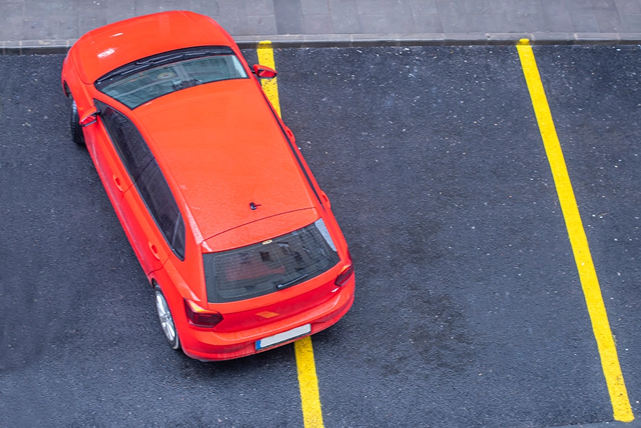 Rotes Auto hat auf zwei Spuren geparkt.